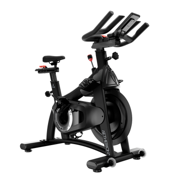 A black indoor cycling machine with a digital display screen on the handlebars, shown against a solid white background.