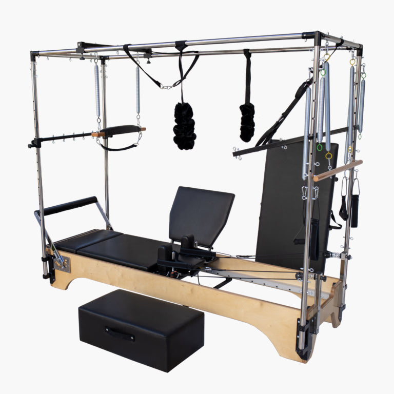 SET Pilates SECR Wooden Cadillac Reformer Trapeze Table with wooden frame, black padded carriage and seat, hanging resistance bands, and a separate black foam block on a plain light gray background.