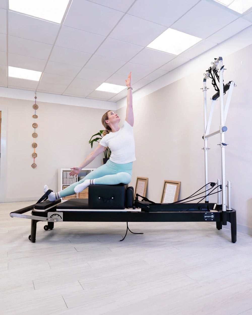 Woman exercising on a Pilates reformer machine in a studio setting.