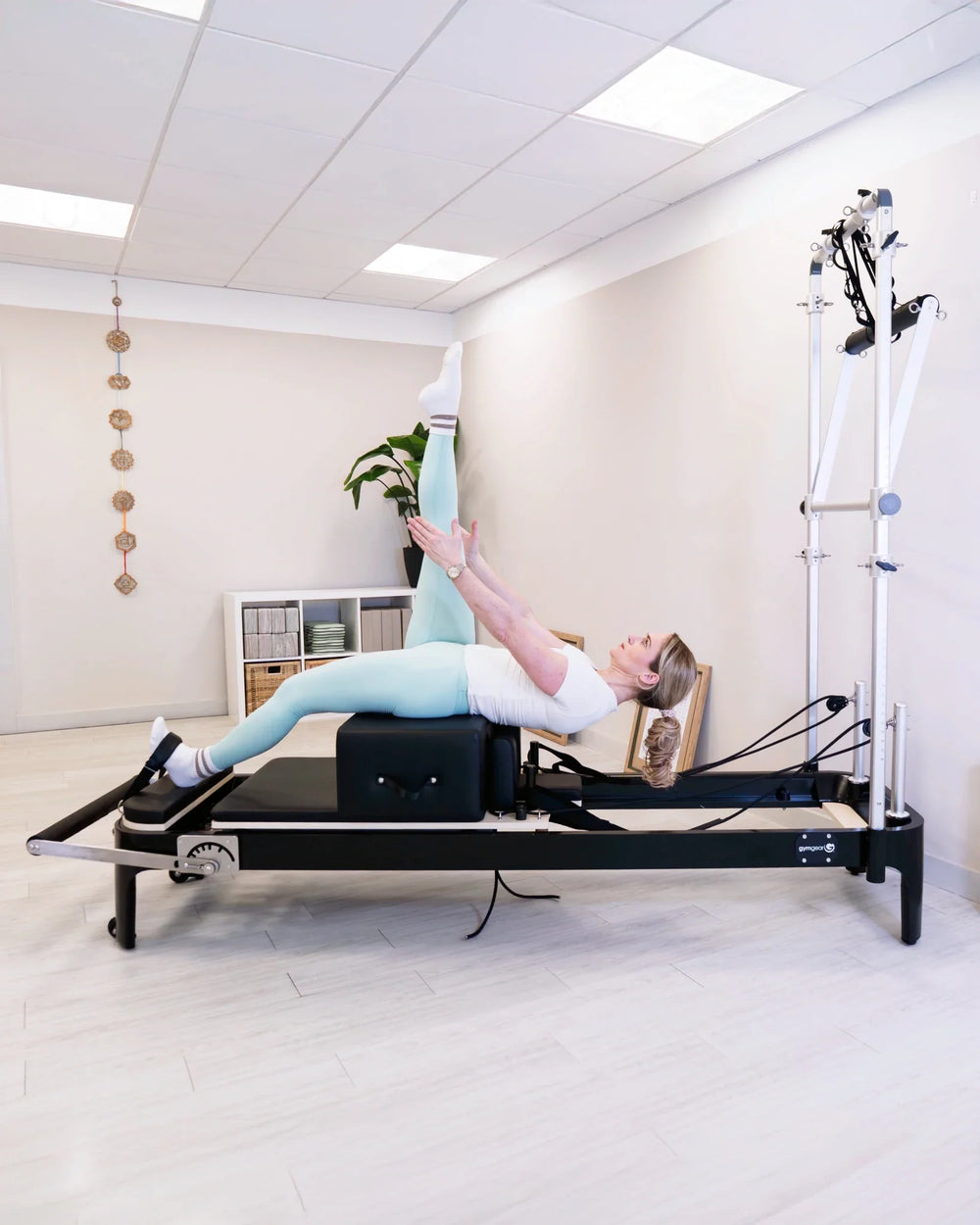 Woman exercising on Gym Gear Aluminium Reformer with Tower System / Half Trapeze machine in a studio setting.