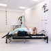 Woman exercising on Gym Gear Aluminium Reformer with Tower System / Half Trapeze machine in a studio setting.