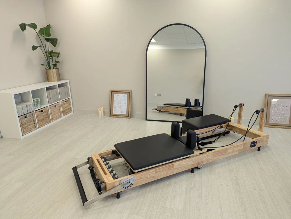 Pilates reformer machine in a room with a mirror and plants
