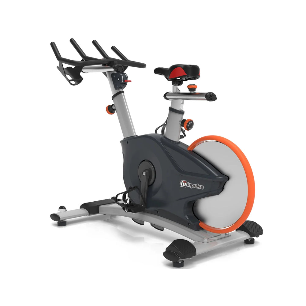 An indoor exercise bike with a dark gray and silver frame, a large gray flywheel with an orange rim, and black handlebars, shown on a white background.
