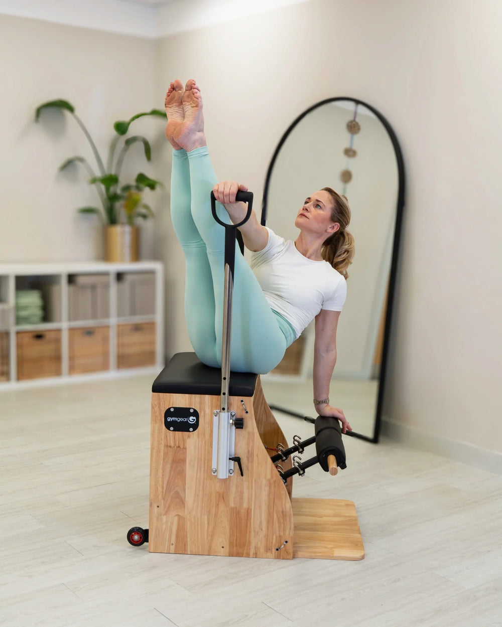 Woman exercising on a Pilates reformer machine in a home setting.