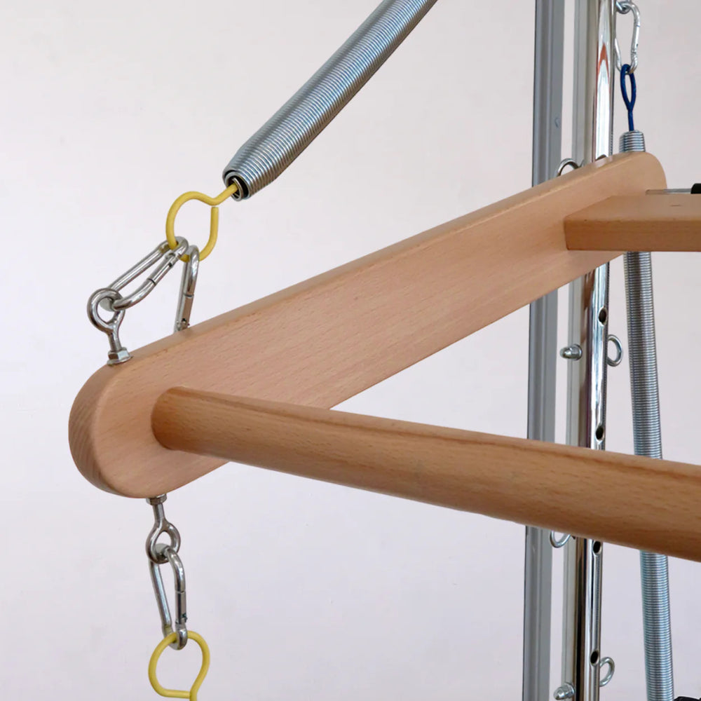 Close-up of a wooden hanger bar suspended from a metal frame with springs and clips against a plain light background.