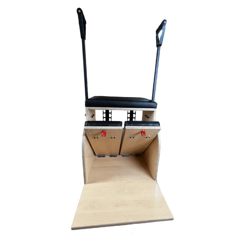 A Pilates reformer machine with a natural wood frame, black padded seat and handles, and metal foot plates, shown against a plain white background.