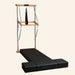 Atro Pilates Wall Tower Unit with Premium Mat with a black padded sliding track, two black foot blocks, and a wooden top bar suspended with straps and a hanging ring.